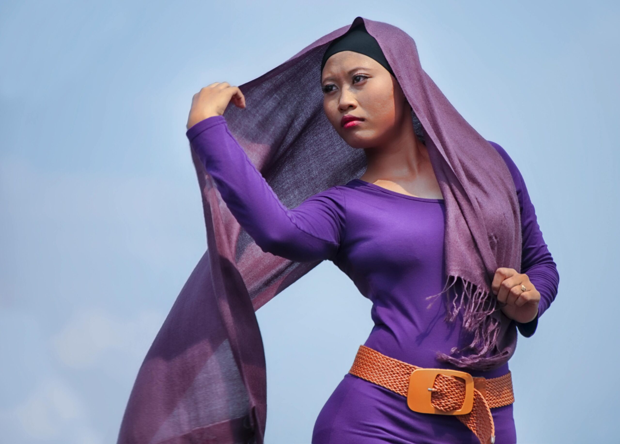 Portrait of an elegant woman wearing a purple dress and scarf outdoors. Fashion and beauty concept.