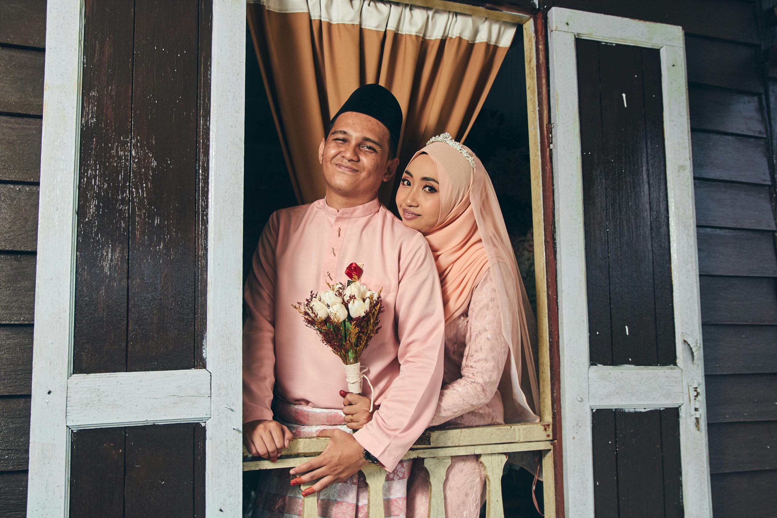 A beautiful Malay couple in traditional attire, capturing a romantic moment on their wedding day.